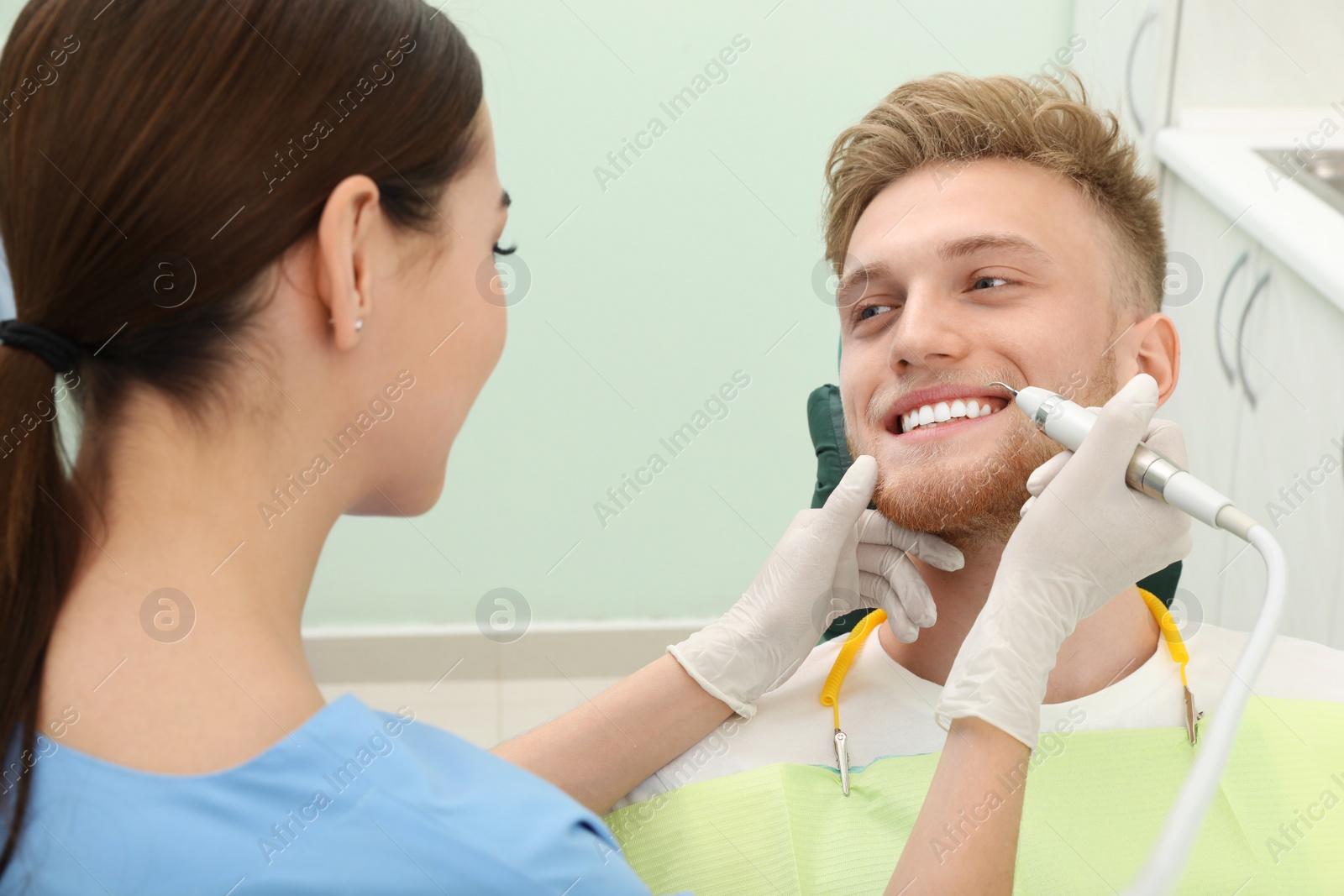 Photo of Professional dentist working with patient in modern clinic. Teeth care