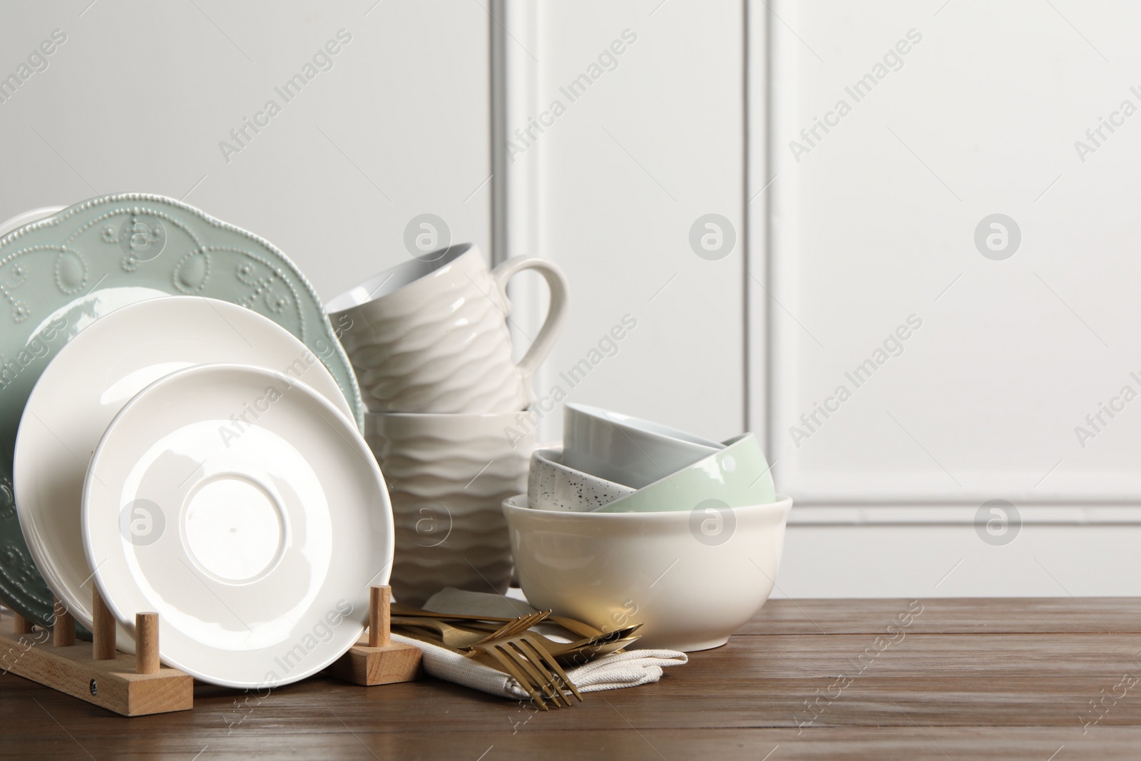 Photo of Beautiful ceramic dishware, cups and cutlery on wooden table, space for text