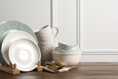 Beautiful ceramic dishware, cups and cutlery on wooden table, space for text