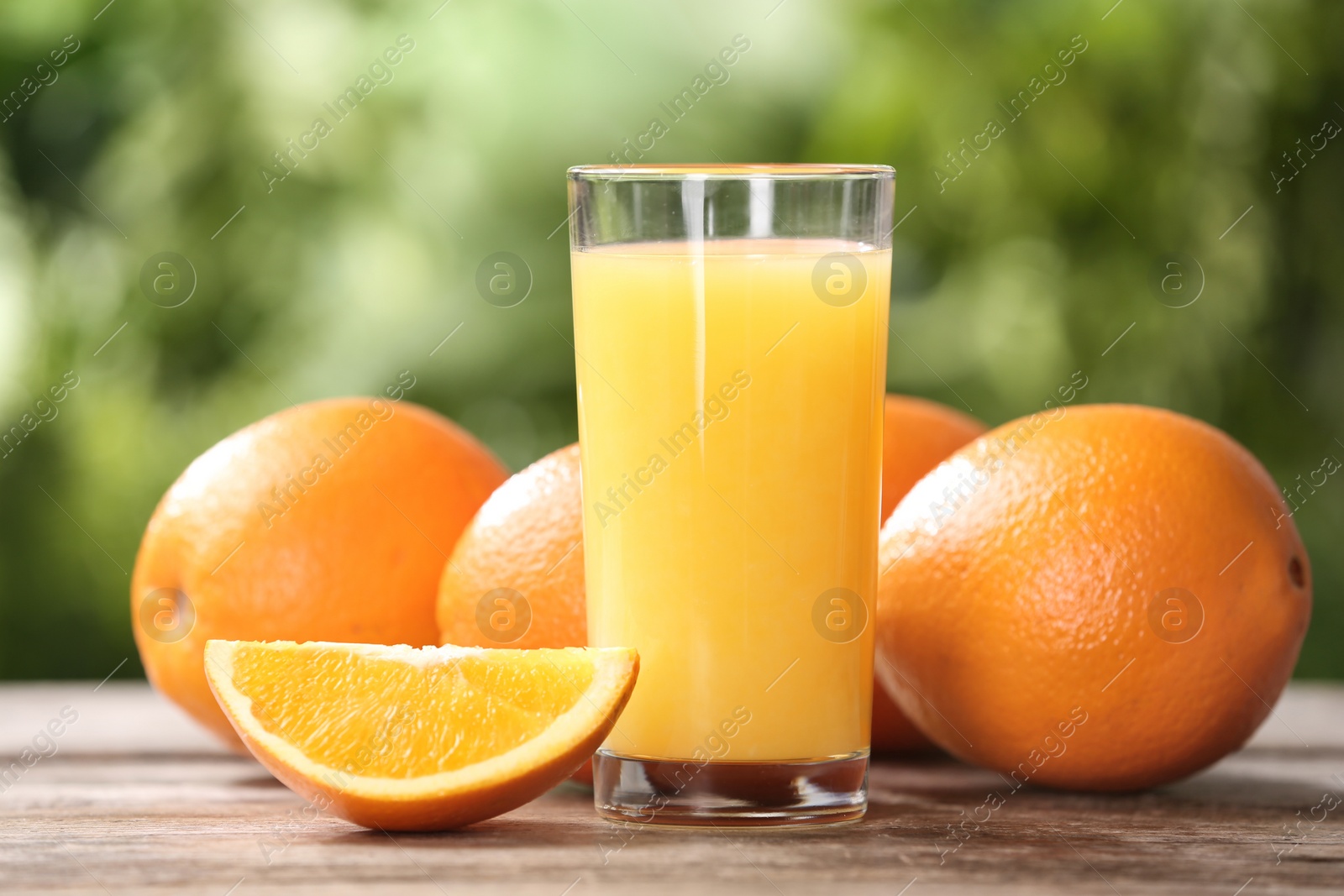 Photo of Glass of fresh juice and oranges on wooden table