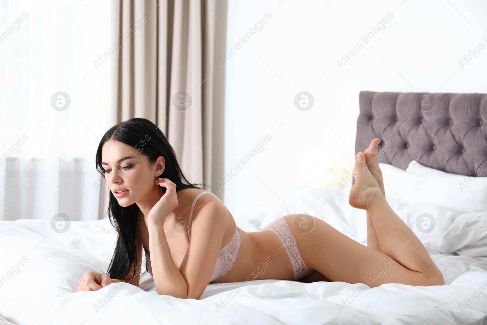 Photo of Beautiful young woman in pink underwear on bed at home