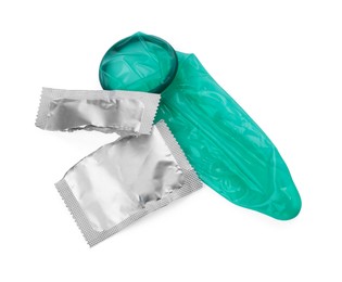 Photo of Unrolled condom and torn package on white background, top view. Safe sex
