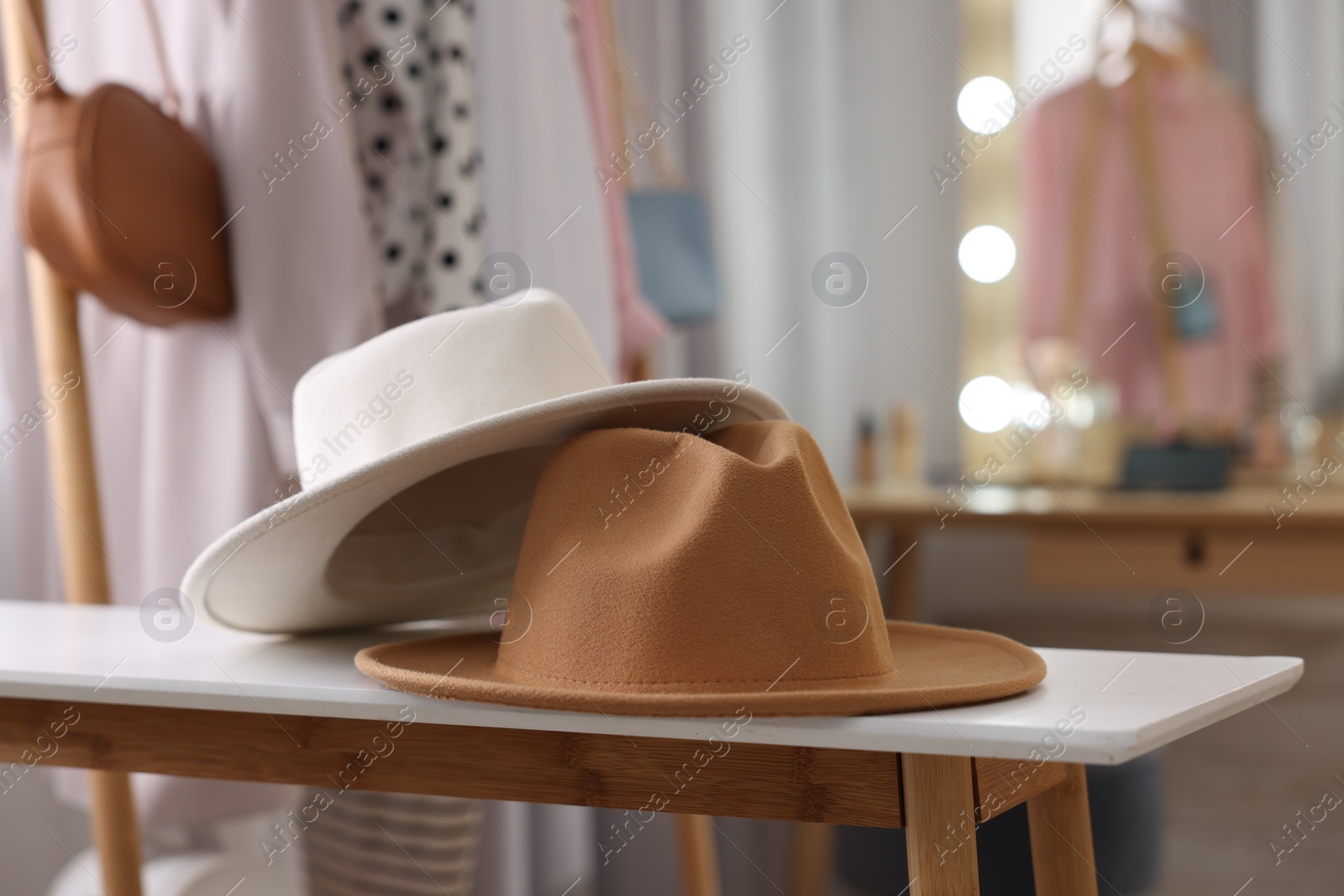 Photo of Stylish hats on white wooden table in makeup room