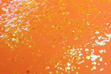 Photo of Shiny bright golden glitter on orange background