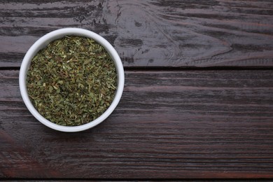 Photo of Dry tarragon in bowl on wooden table, top view. Space for text