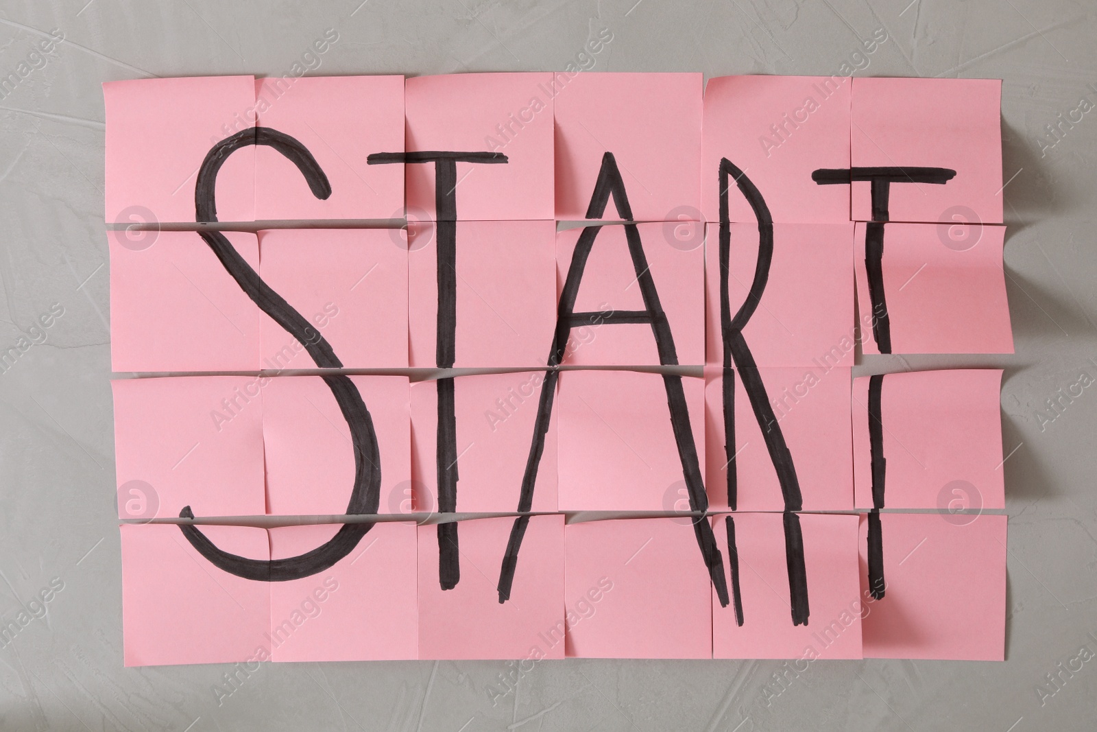 Photo of Pink sticky notes with word Start on light grey stone background, flat lay