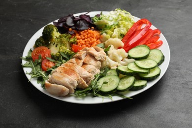 Photo of Balanced diet and healthy foods. Plate with different delicious products on black table