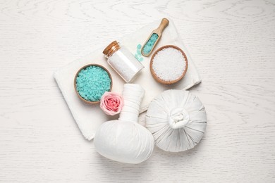 Photo of Flat lay composition of herbal bags and spa products on white wooden table