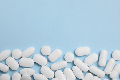 Photo of Many pills on light blue background, flat lay. Space for text