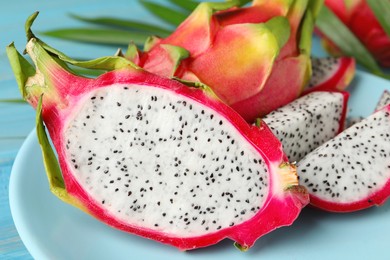 Plate with delicious cut and whole white pitahaya fruits on table, closeup