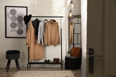 Photo of Stylish warm clothes on rack in dressing room interior