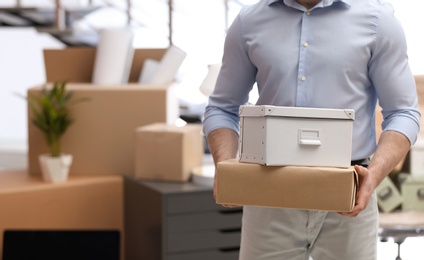 Man holding moving boxes in new office, closeup. Space for text