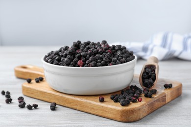 Photo of Bowl and scoop with dried blueberries on white wooden table