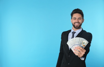 Portrait of happy young businessman with money on color background. Space for text
