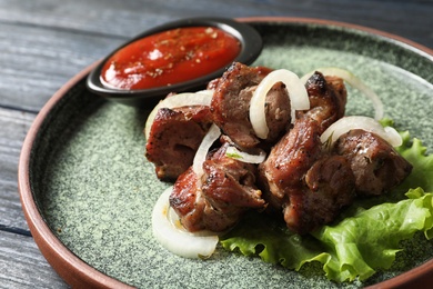 Plate with shish kebab and sauce on table, closeup