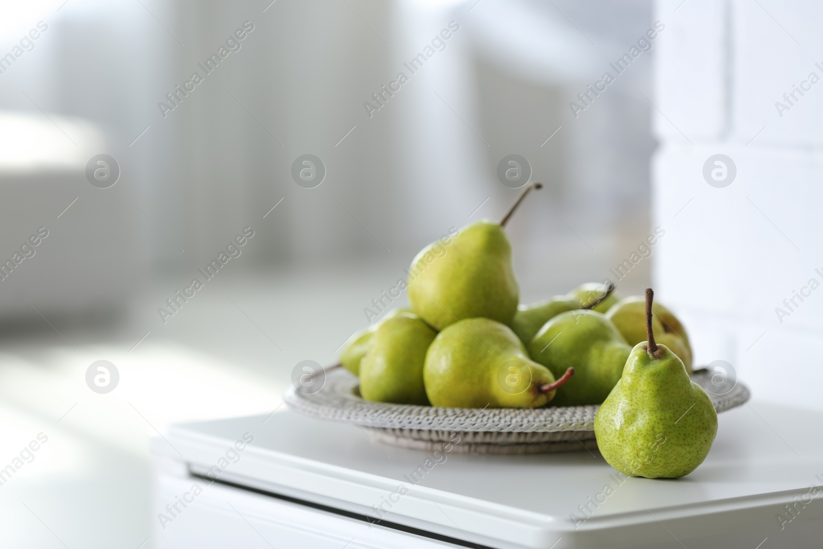 Photo of Fresh ripe pears on white table in room. Space for text