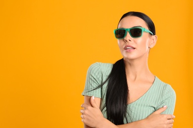 Photo of Beautiful woman wearing sunglasses on yellow background. Space for text