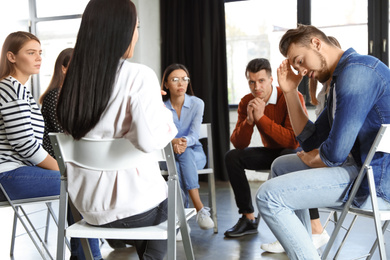 Photo of Psychotherapist working with patients in group therapy session indoors