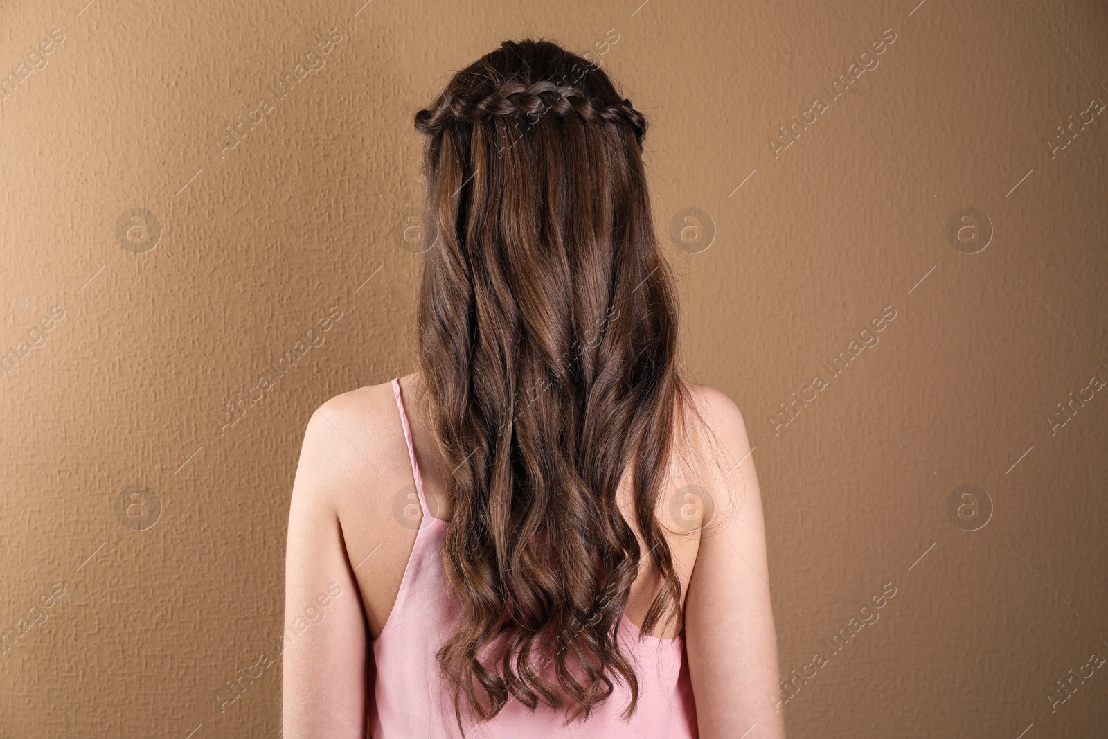 Photo of Woman with braided hair on light brown background, back view