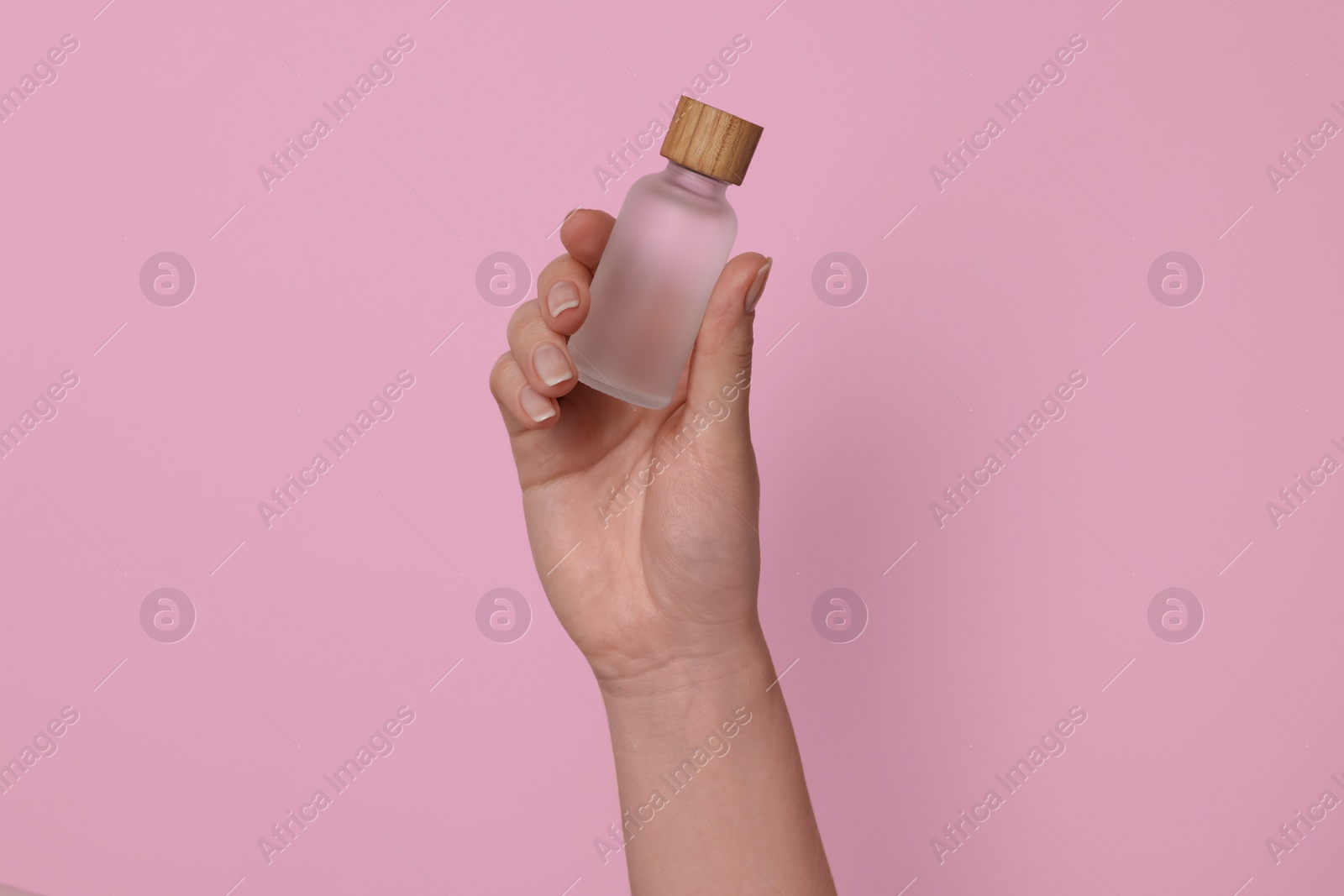 Photo of Woman holding bottle of cosmetic product on pink background, closeup