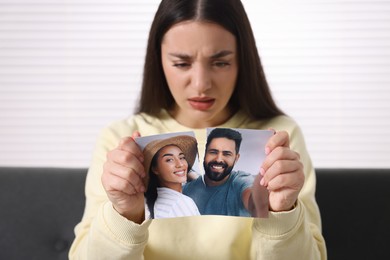 Photo of Upset woman ripping photo indoors, focus on picture. Divorce concept