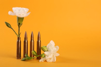Photo of Bullets and beautiful flowers on yellow background, space for text