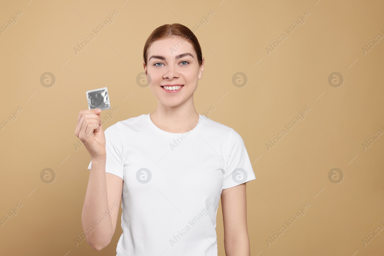 Photo of Woman holding condom on beige background, space for text. Safe sex