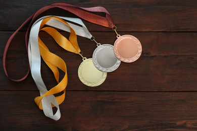 Gold, silver and bronze medals on wooden background, flat lay. Space for design