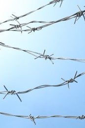 Metal barbed wire on light blue background