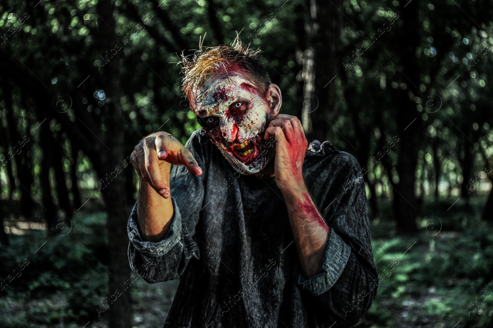 Photo of Scary zombie with bloody face outdoors. Halloween monster