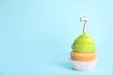 Photo of Birthday cupcake with number seven candle on blue background, space for text