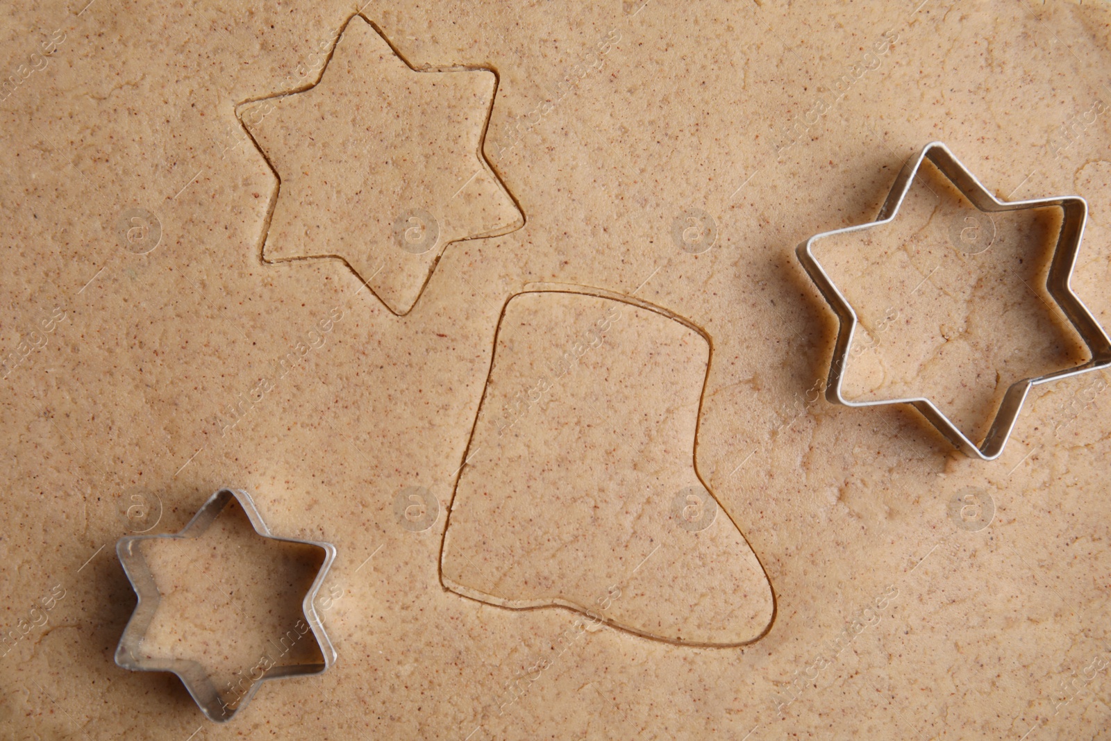 Photo of Homemade Christmas biscuits. Cookie cutters on raw dough, flat lay