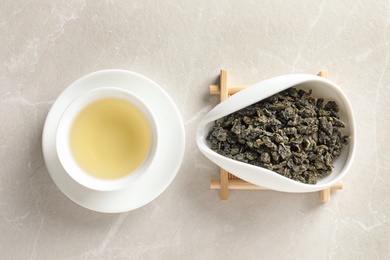 Photo of Cup of Tie Guan Yin oolong and chahe with tea leaves on table, top view