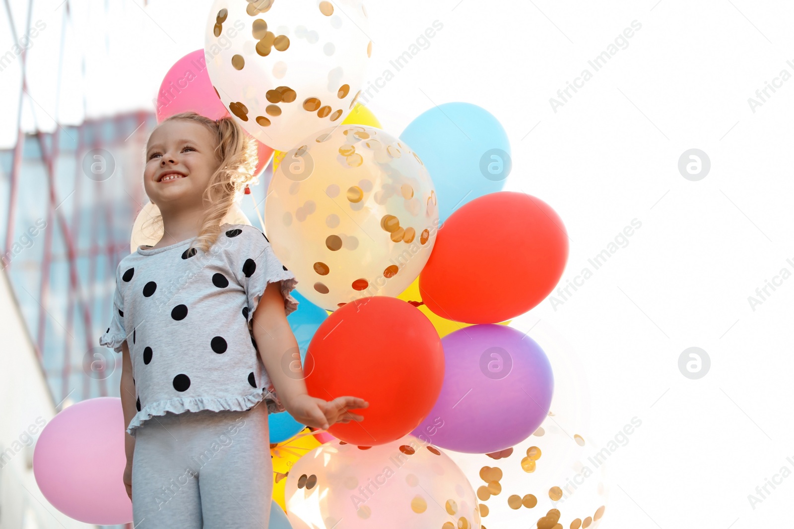 Photo of Cute little girl with colorful balloons outdoors on sunny day