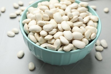 Photo of Raw white beans on light grey table, closeup