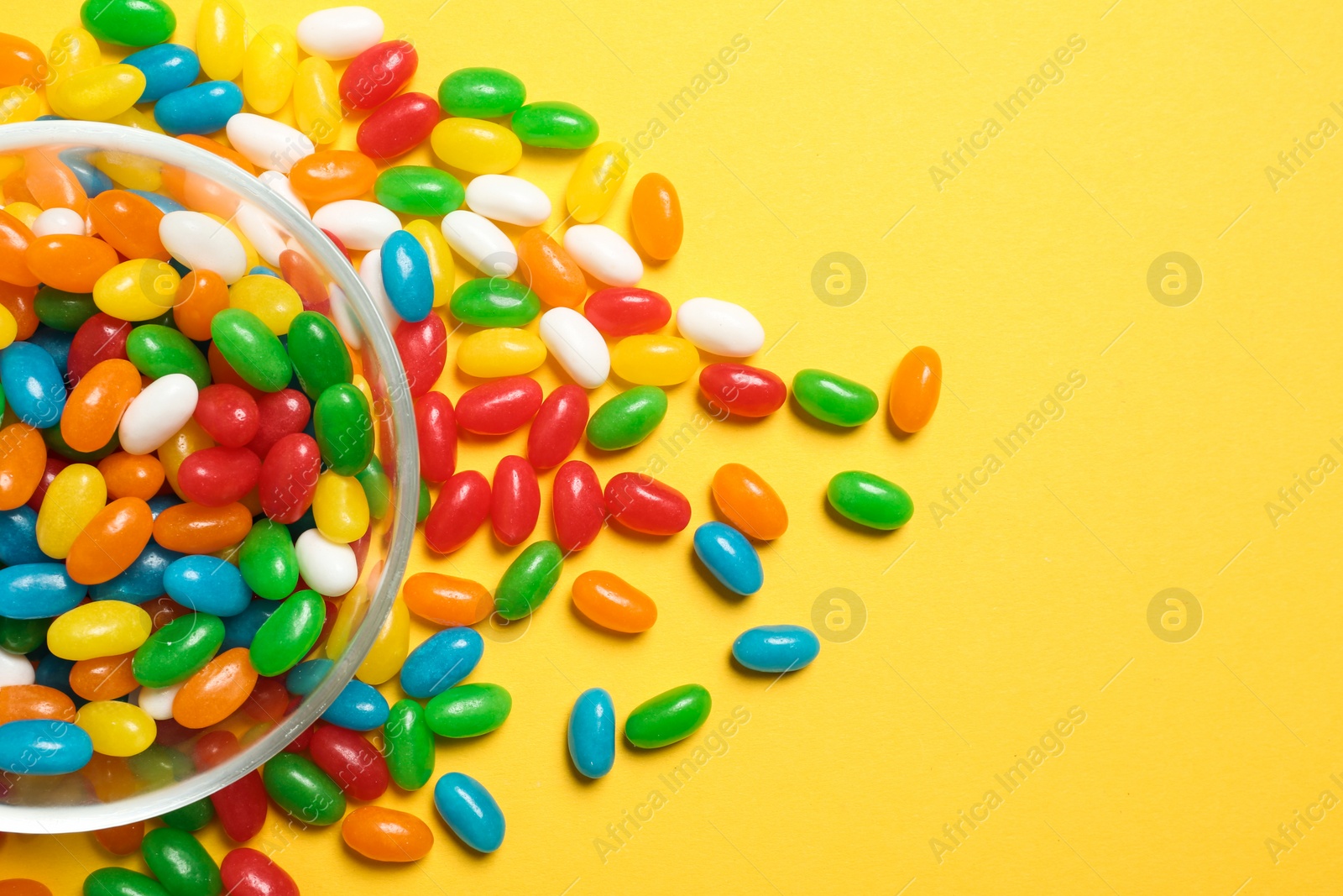 Photo of Bowl of jelly beans on color background, top view. Space for text