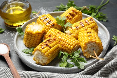 Photo of Delicious grilled corn cobs on grey table