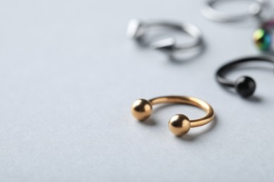 Photo of Stylish golden horseshoe ring on light grey background, closeup with space for text. Piercing jewelry