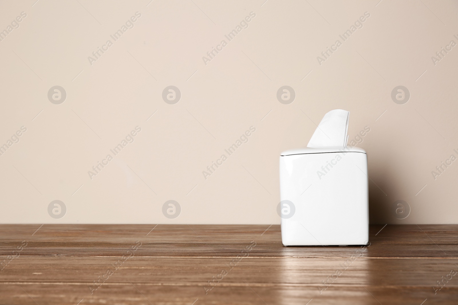 Photo of Napkin holder with paper serviettes on table against color background. Space for text