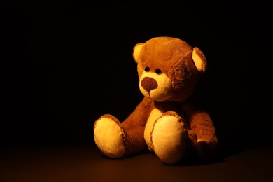 Cute lonely teddy bear on dark background. Space for text