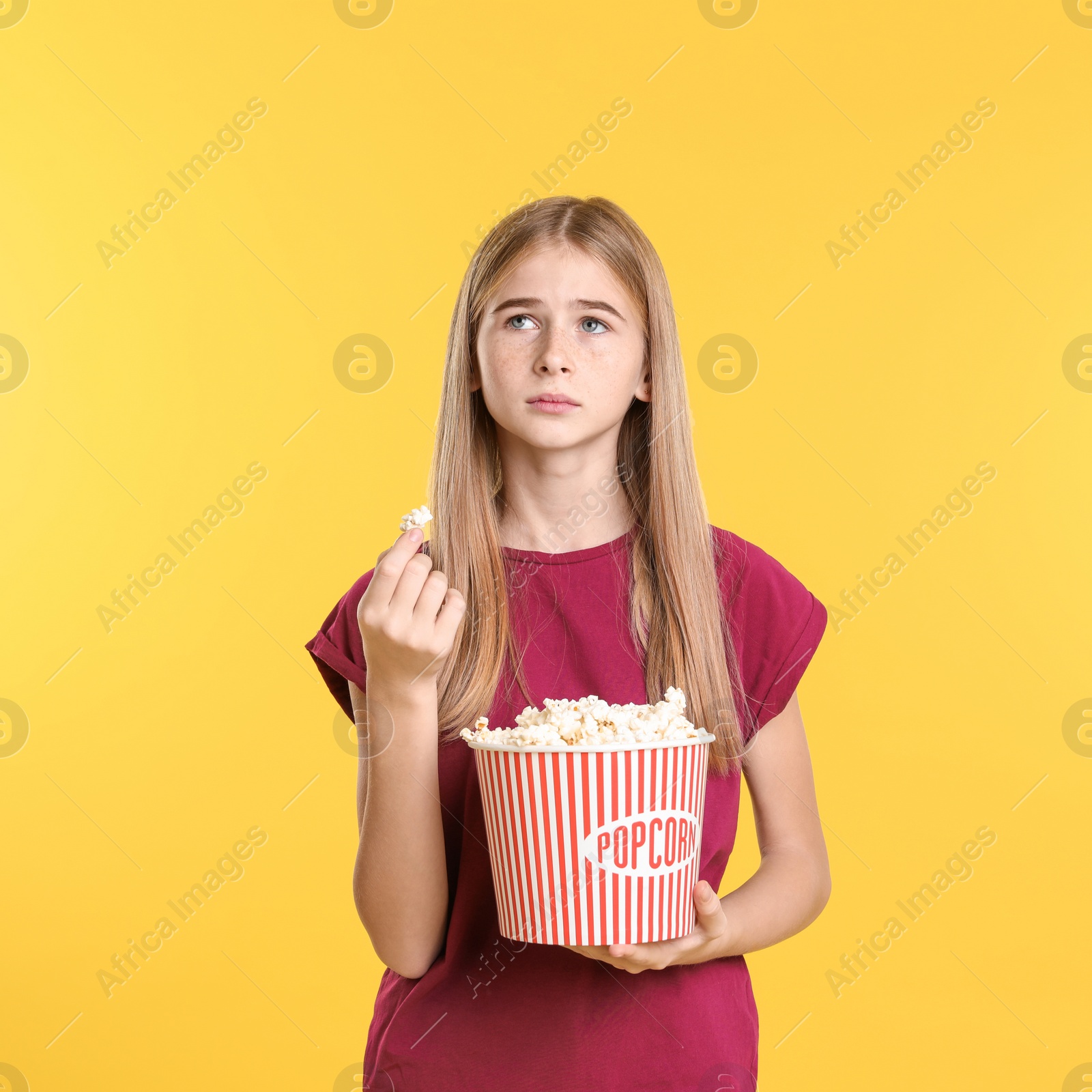 Photo of Teenage girl with popcorn during cinema show on color background