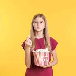 Teenage girl with popcorn during cinema show on color background