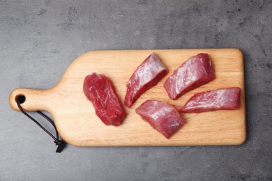 Photo of Board with raw meat on grey background, top view