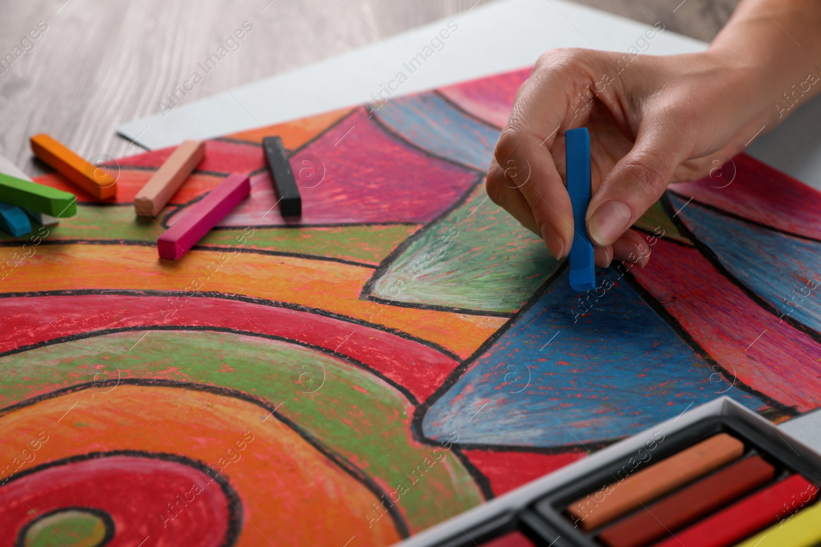 Photo of Woman drawing abstract mountain landscape with soft pastel at table, closeup