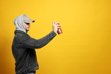 Photo of Handsome man holding can of spray paint on yellow background. Space for text