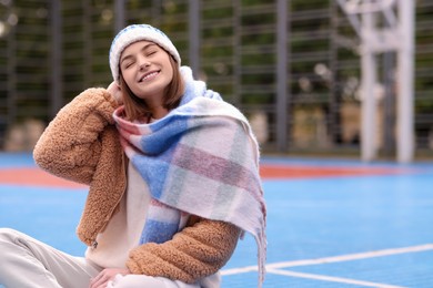 Beautiful woman in warm scarf and hat outdoors, space for text