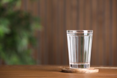 Photo of Glass of clean water on wooden table indoors, space for text