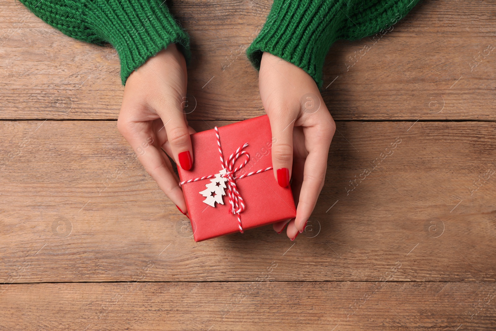 Photo of Christmas present. Woman with gift box at wooden table, top view