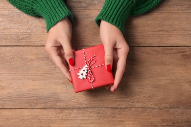 Photo of Christmas present. Woman with gift box at wooden table, top view