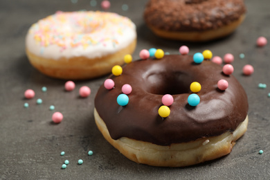 Photo of Yummy donut with colorful sprinkles on dark table, closeup